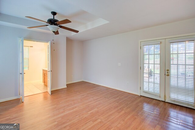 spare room featuring light wood-type flooring, a ceiling fan, baseboards, and french doors