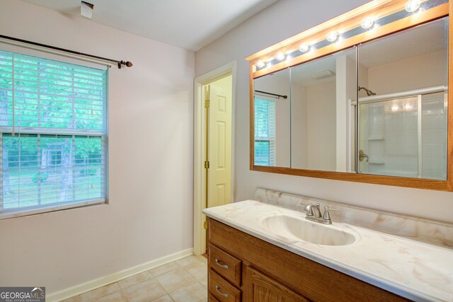 full bathroom with plenty of natural light, vanity, baseboards, and a shower with door