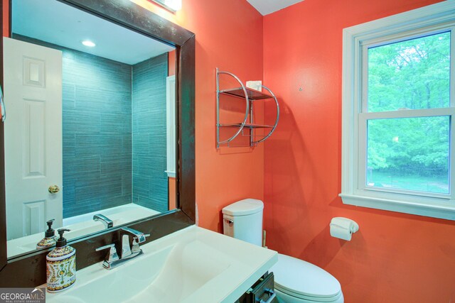 bathroom featuring a wealth of natural light, toilet, and vanity