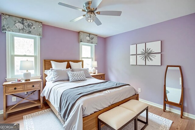 bedroom with light wood-style flooring, baseboards, and ceiling fan