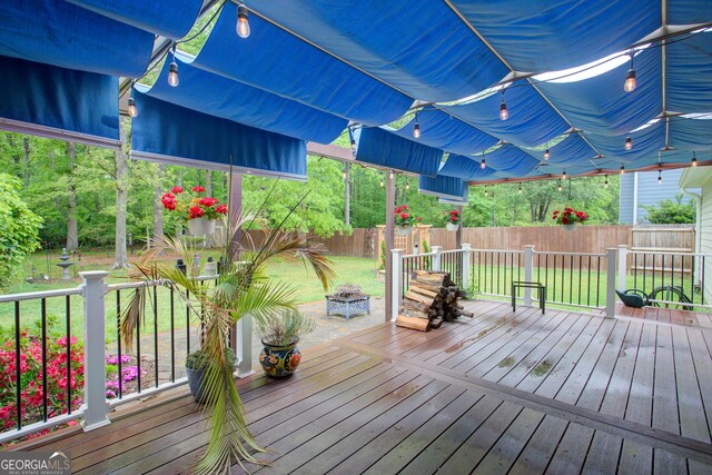 deck featuring a fenced backyard, an outdoor fire pit, and a yard