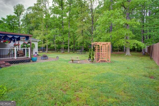 view of yard featuring a fire pit, a wooden deck, and a fenced backyard
