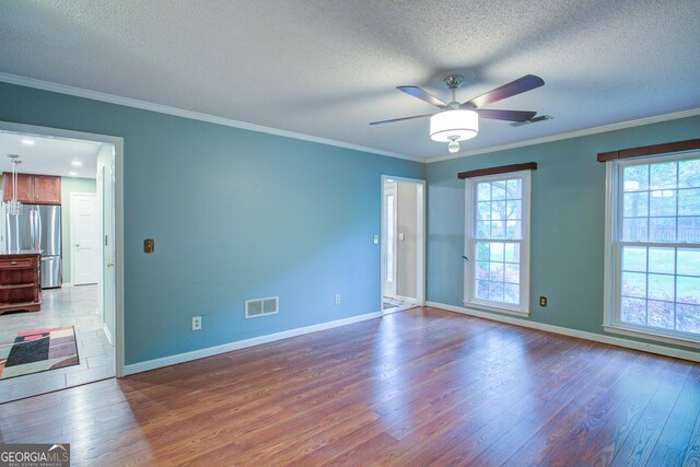 empty room with ceiling fan, wood finished floors, visible vents, and a textured ceiling