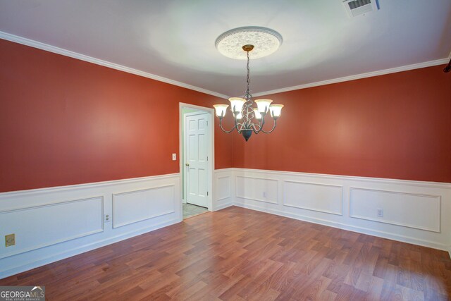 unfurnished room featuring wainscoting, a notable chandelier, wood finished floors, and visible vents