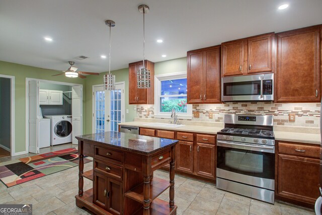 kitchen featuring decorative backsplash, washer and dryer, a sink, and appliances with stainless steel finishes