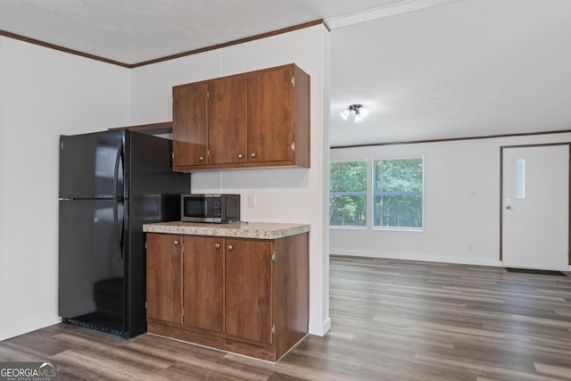 138 Forest Hill Dr, Eatonton, GA 31024 - kitchen with crown molding, freestanding refrigerator, brown cabinetry, stainless steel microwave, and dark wood-type flooring