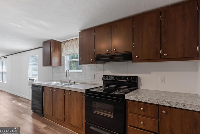 138 Forest Hill Dr, Eatonton, GA 31024 - kitchen with light countertops, under cabinet range hood, a sink, light wood-style floors, and black appliances