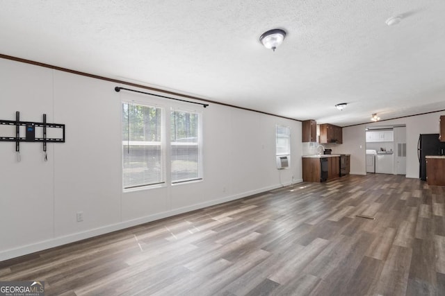 138 Forest Hill Dr, Eatonton, GA 31024 - unfurnished living room featuring washing machine and dryer, wood finished floors, a textured ceiling, lofted ceiling, and baseboards