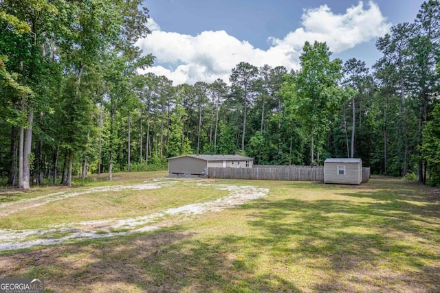 138 Forest Hill Dr, Eatonton, GA 31024 - view of yard with a storage unit, an outdoor structure, fence, and a wooded view
