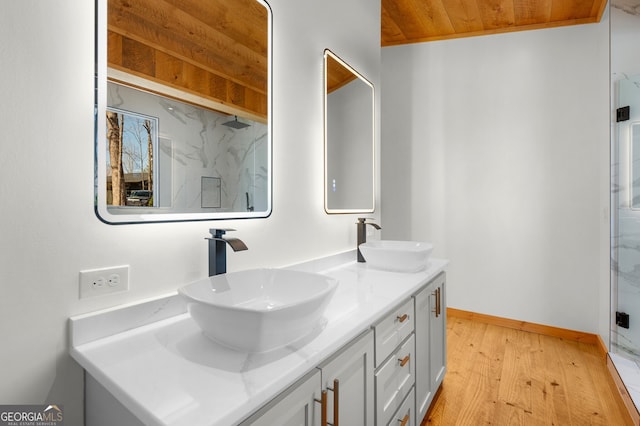 full bath with baseboards, wood finished floors, a sink, and double vanity