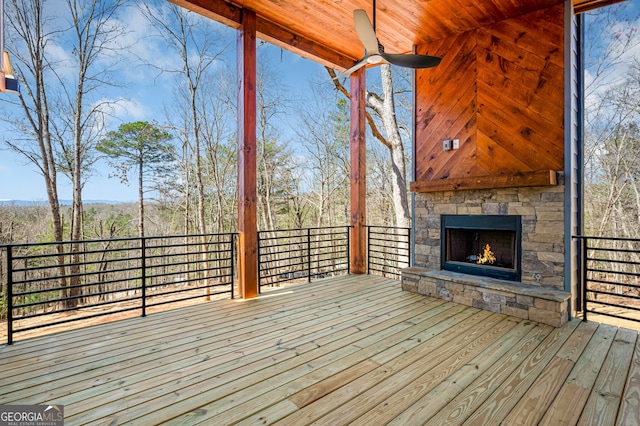 wooden deck with an outdoor stone fireplace