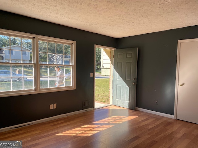 interior space with baseboards, visible vents, wood finished floors, and a textured ceiling