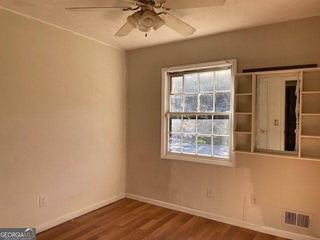 unfurnished room with wood finished floors, a textured ceiling, baseboards, visible vents, and ceiling fan