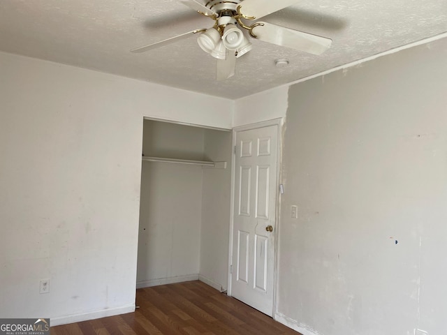 unfurnished bedroom featuring a closet, a textured ceiling, baseboards, wood finished floors, and a ceiling fan