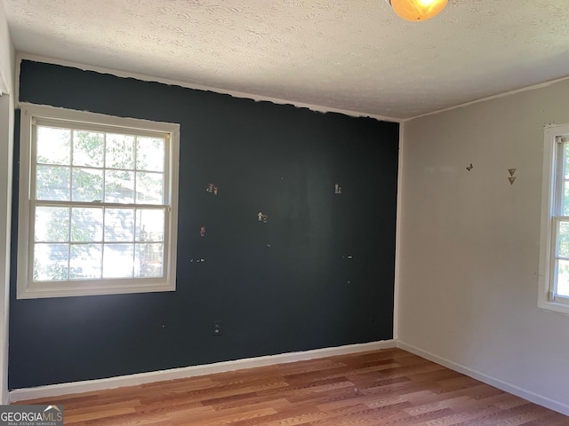 unfurnished room featuring a textured ceiling, baseboards, and wood finished floors