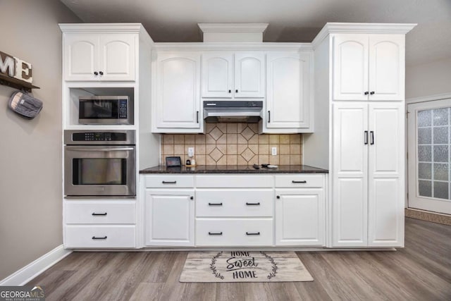 kitchen featuring under cabinet range hood, dark wood-style flooring, white cabinetry, and appliances with stainless steel finishes