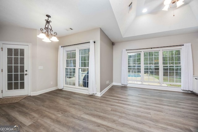 spare room featuring visible vents, baseboards, an inviting chandelier, and wood finished floors