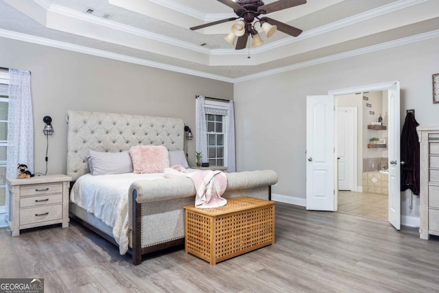 bedroom featuring crown molding, a tray ceiling, wood finished floors, and visible vents