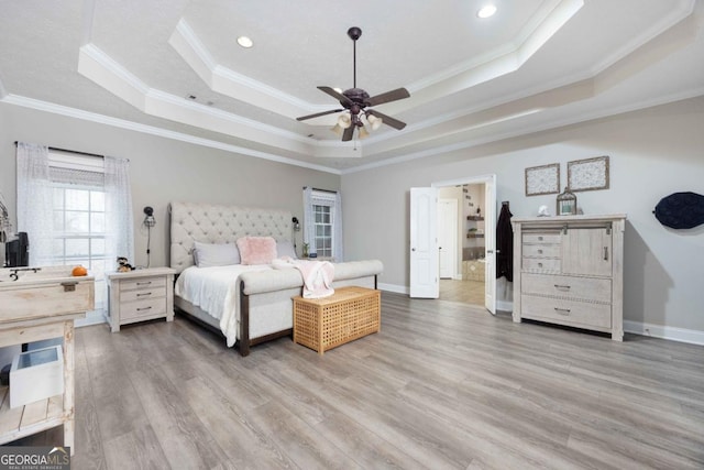 bedroom featuring a tray ceiling, crown molding, light wood finished floors, and baseboards