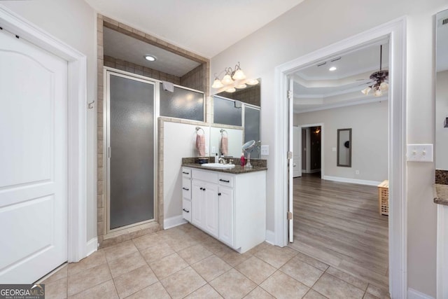 full bath with a tray ceiling, tile patterned floors, a stall shower, and vanity