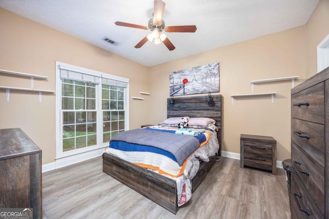 bedroom with wood finished floors, baseboards, a ceiling fan, and visible vents