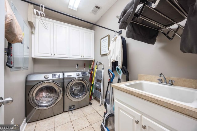 clothes washing area featuring light tile patterned floors, visible vents, a sink, cabinet space, and washer and clothes dryer