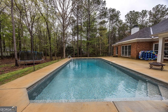 outdoor pool featuring a trampoline and a patio