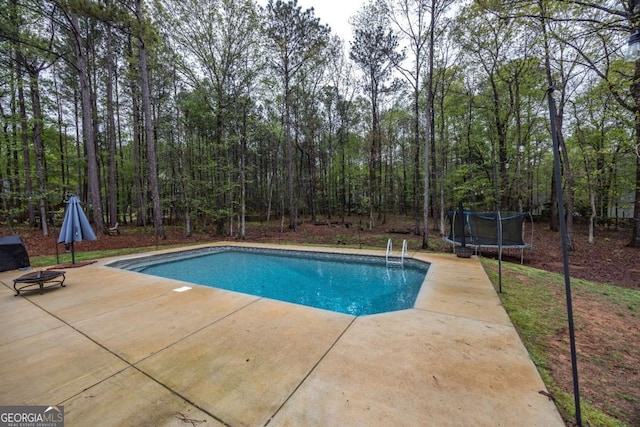 pool with an outdoor fire pit, a trampoline, and a patio