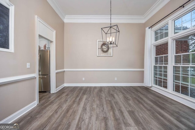 unfurnished dining area featuring a chandelier, crown molding, wood finished floors, and baseboards