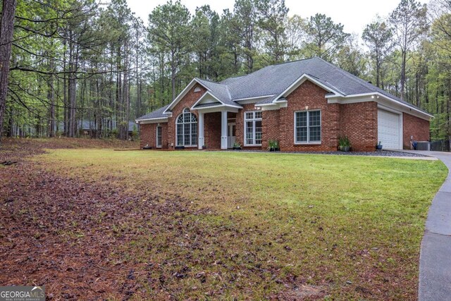 view of front facade with a garage, a front yard, brick siding, and roof with shingles