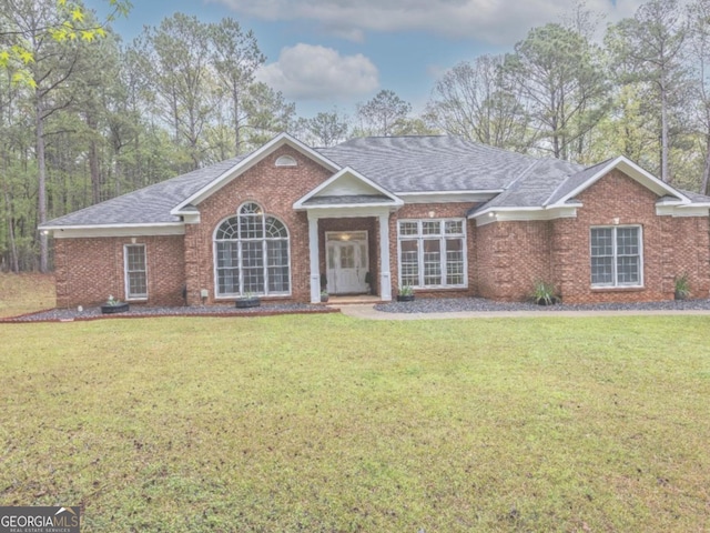 single story home with brick siding, a front yard, and roof with shingles
