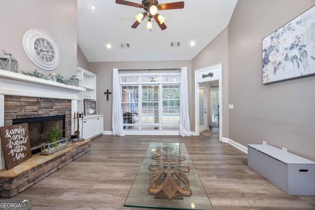 living area featuring ceiling fan, high vaulted ceiling, visible vents, wood finished floors, and baseboards