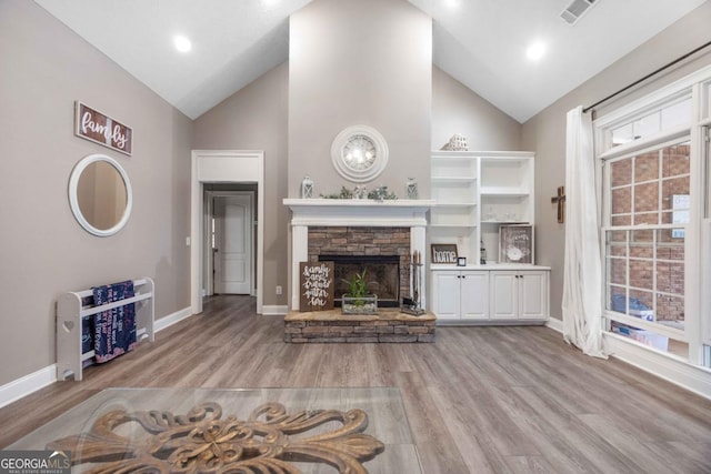 unfurnished living room with light wood-style flooring, high vaulted ceiling, a fireplace, and baseboards