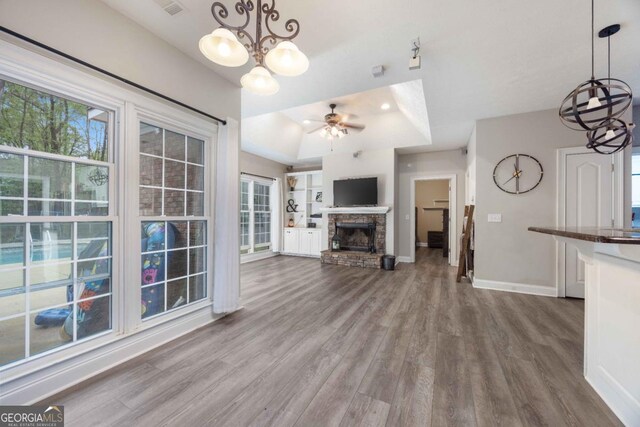 unfurnished living room with plenty of natural light, baseboards, ceiling fan with notable chandelier, and wood finished floors