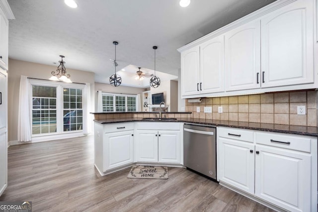 kitchen featuring decorative backsplash, a peninsula, stainless steel dishwasher, and white cabinetry