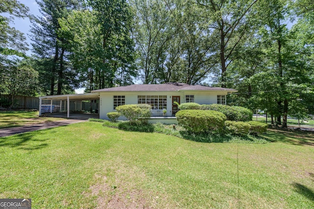 ranch-style house with fence, stucco siding, an attached carport, a front lawn, and driveway