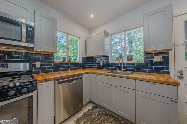 kitchen with stainless steel appliances, recessed lighting, butcher block counters, tasteful backsplash, and a sink