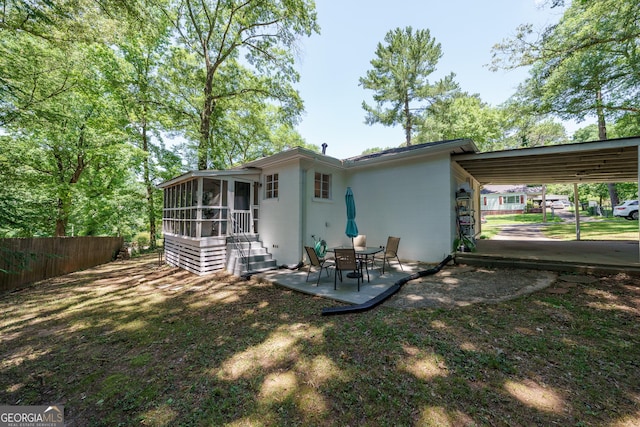 rear view of house with a patio, a sunroom, fence, and concrete block siding