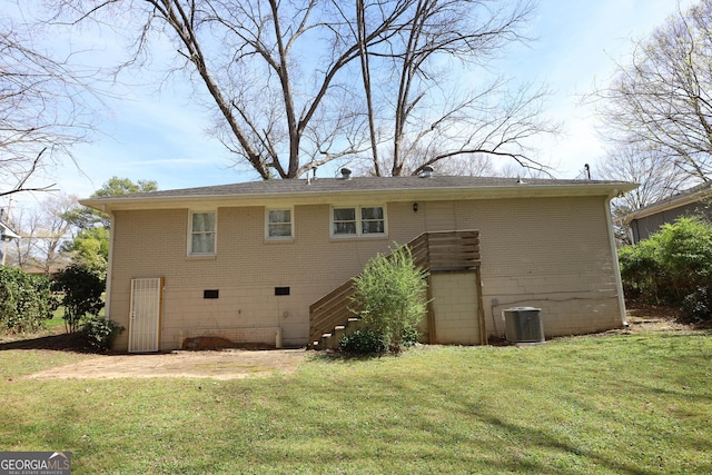 back of property featuring brick siding, cooling unit, stairway, and a yard