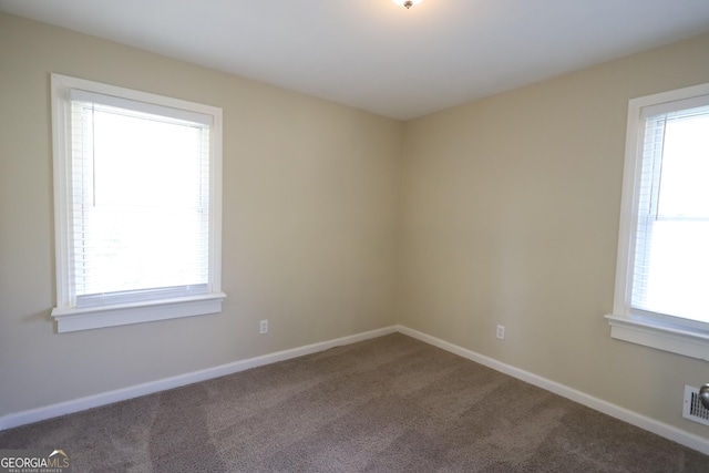spare room featuring baseboards, a healthy amount of sunlight, and carpet