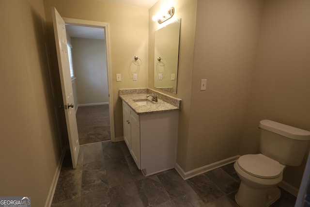 bathroom with toilet, vanity, and baseboards