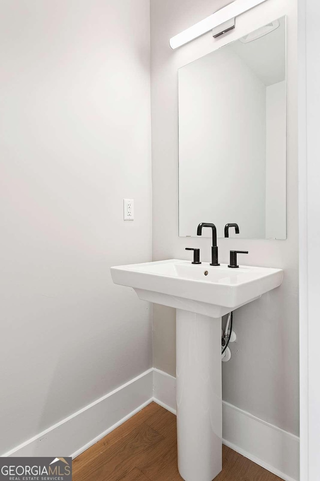 bathroom featuring baseboards, wood finished floors, and a sink