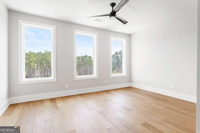 spare room with light wood-type flooring, baseboards, and a ceiling fan