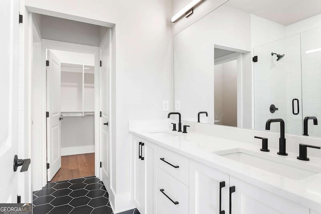 bathroom with a stall shower, double vanity, a walk in closet, and tile patterned flooring
