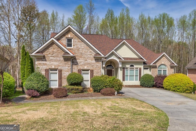 craftsman-style house featuring brick siding, a front lawn, and roof with shingles