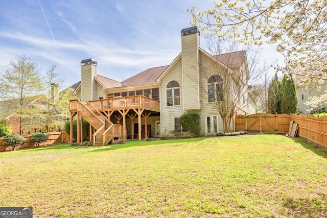 back of property with a fenced backyard, a lawn, a chimney, and a deck