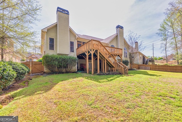 rear view of property featuring stairs, a chimney, a deck, fence, and a lawn