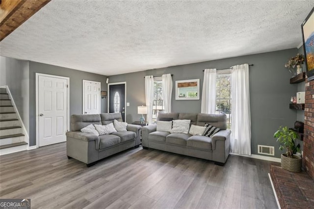 living area with stairs, dark wood-type flooring, baseboards, visible vents, and a fireplace
