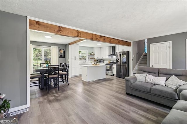 living area featuring wood finished floors, baseboards, stairs, and a textured ceiling