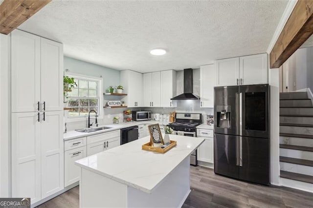 kitchen with dark wood-style flooring, stainless steel appliances, a sink, wall chimney range hood, and a center island